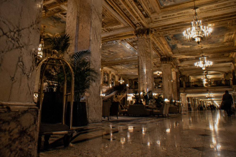 Historic hotel lobby interior with ornate gilded ceiling and marble columns under warm lights