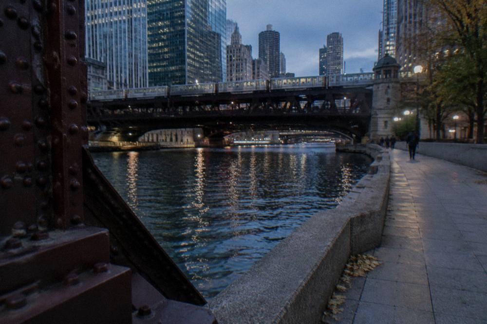 A historical plaque on the Chicago Riverwalk at dusk beside the LaSalle Street bridge
