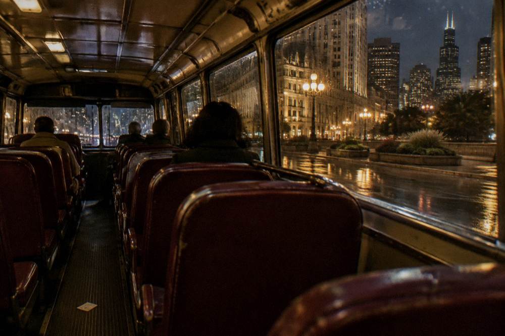 A vintage-style tour coach interior with rows of seats seen from the back at night