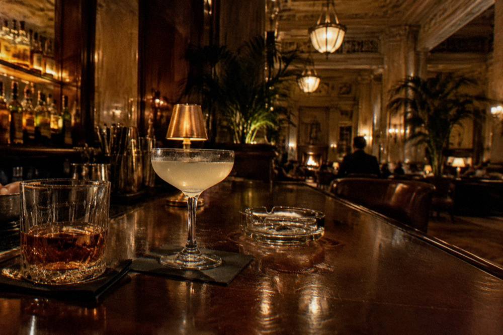 Dark wood bar top with glasses and a glowing backbar in a Prohibition-era Chicago lounge