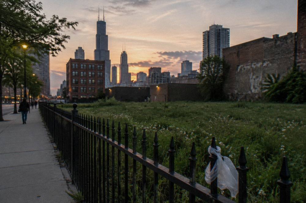 Dark wrought-iron fence and empty lawn on a Chicago residential block at dusk