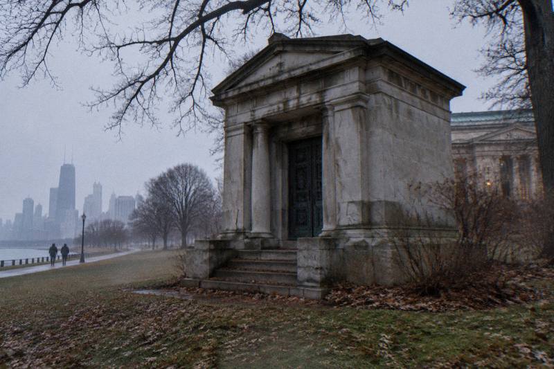 Weathered limestone Couch Tomb in Lincoln Park at gray dusk with bare oak branches overhead