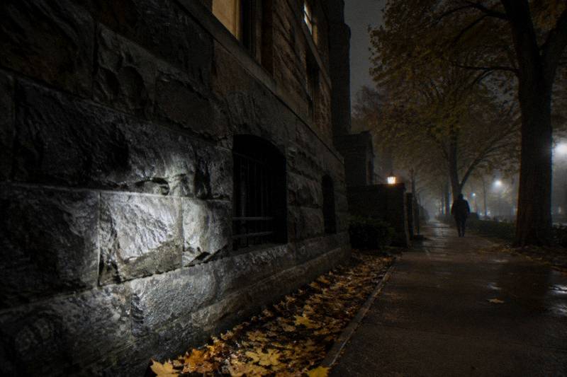 Flashlight beam across the dark rusticated stone wall of Glessner House on Prairie Avenue at midnight