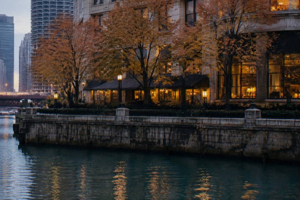 A dim evening view of a Chicago riverfront street with autumn trees and lit windows