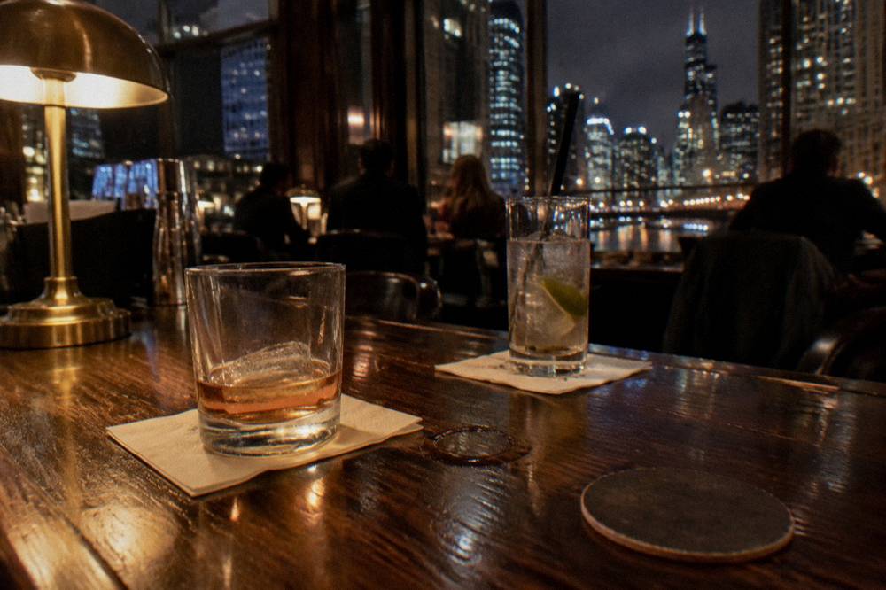 Two covered drinks on a wooden bar top in low warm light