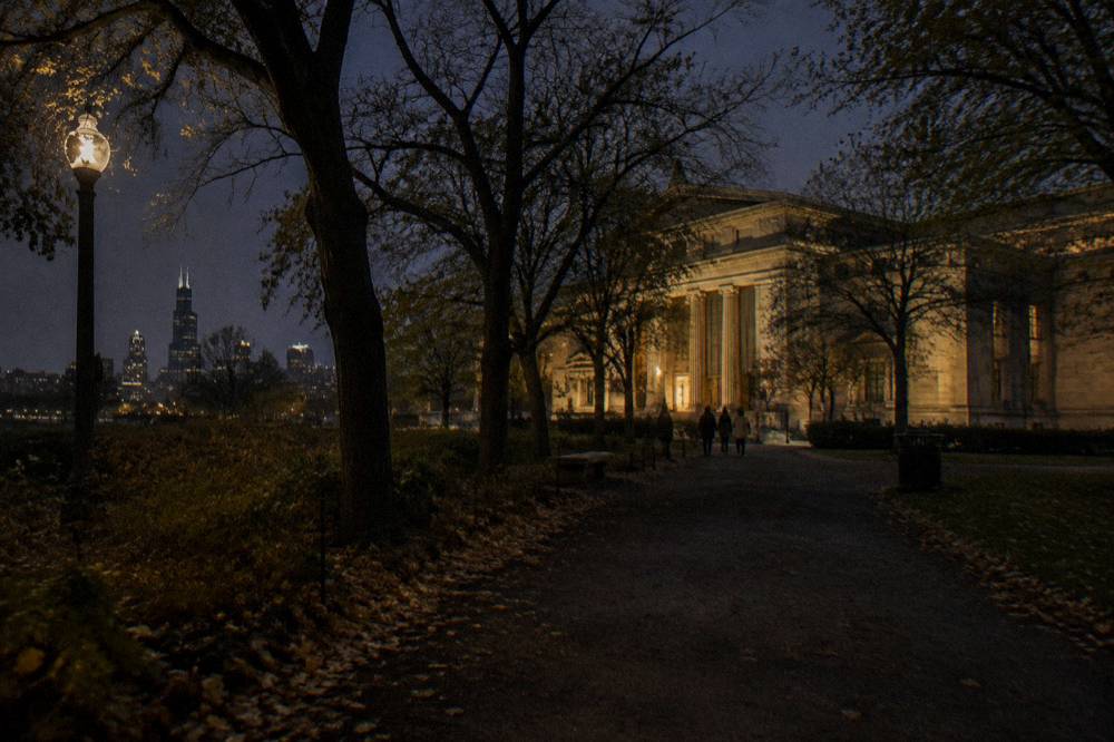 Dark tree-lined path in Lincoln Park at night with a distant museum building lit