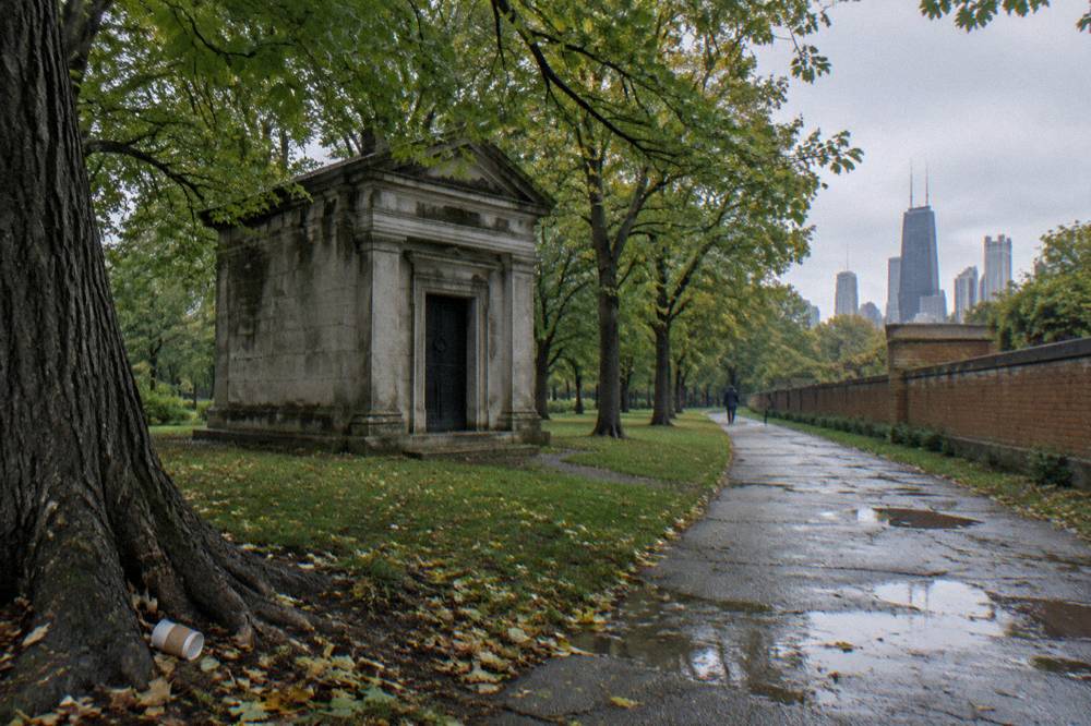 Stone mausoleum standing among trees behind a museum building in a Chicago park