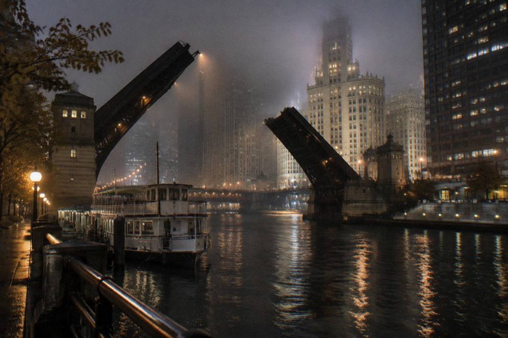 Dark Chicago cityscape at night with historic hotel towers lit above the river