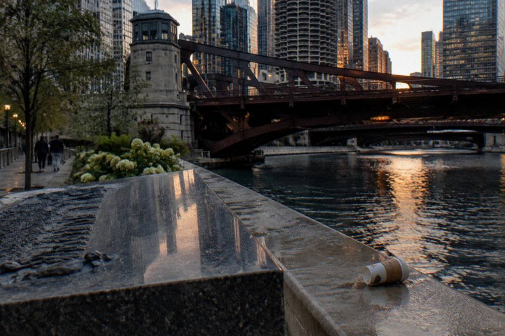 Granite historical marker on the Chicago Riverwalk at dusk with the bridge above