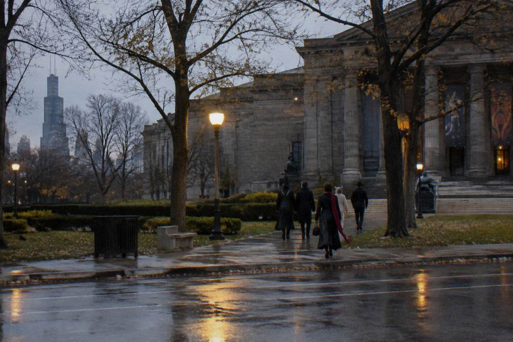 A group of adults in costume walking together down a lamplit Lincoln Park street.