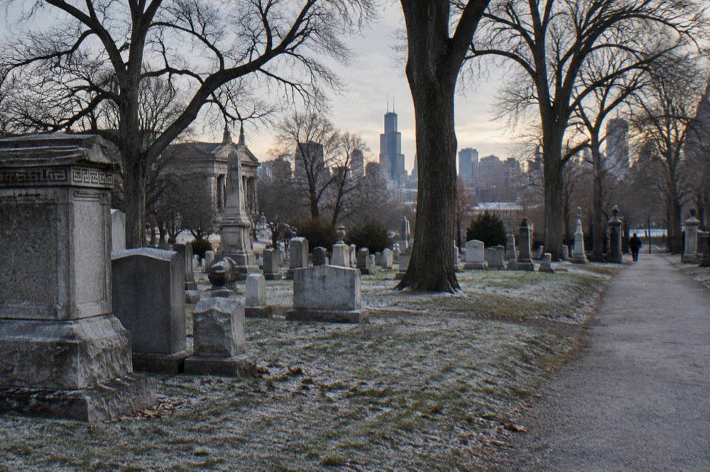 Rows of old headstones and bare trees inside a quiet cemetery